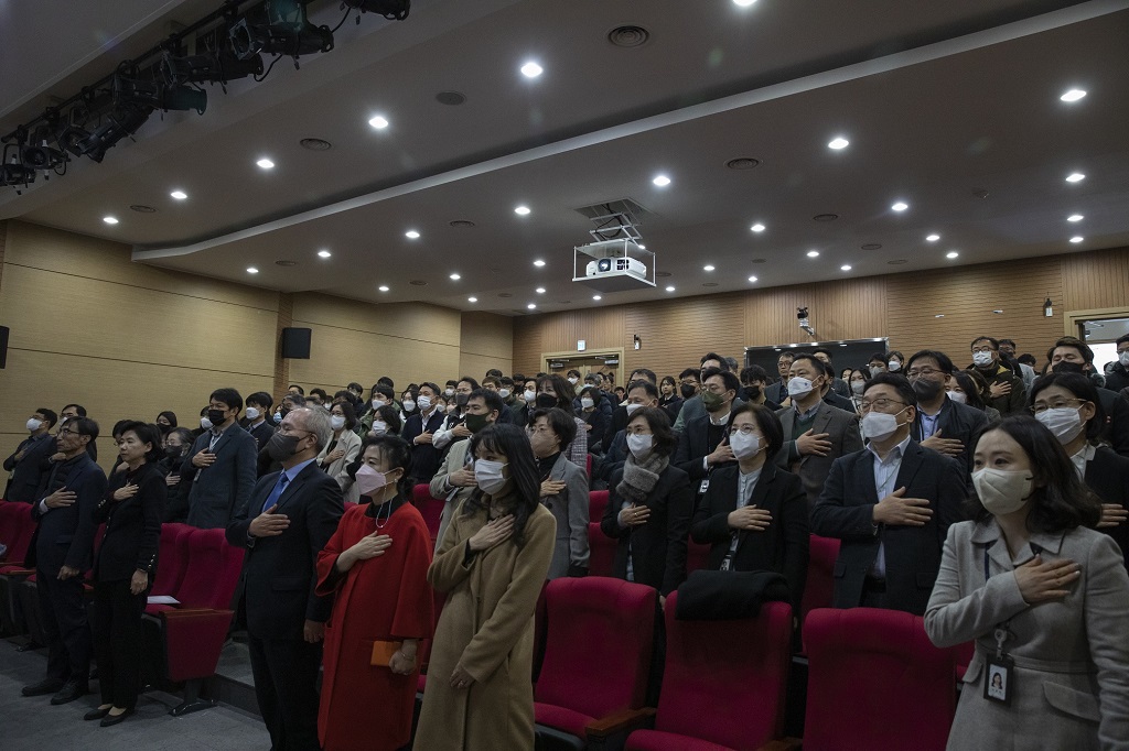 권준욱 원장 이임식에서 오른손을 왼쪽 가슴에 붙여 경례를 하는 사람들의 단체 사진